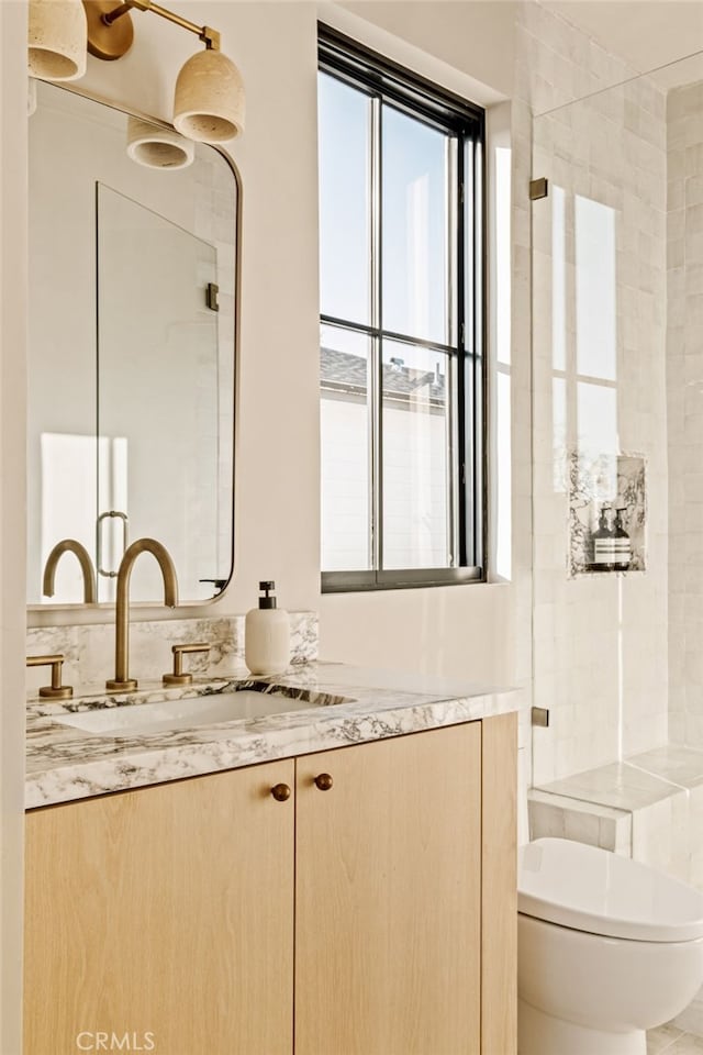 bathroom featuring toilet, a tile shower, and vanity