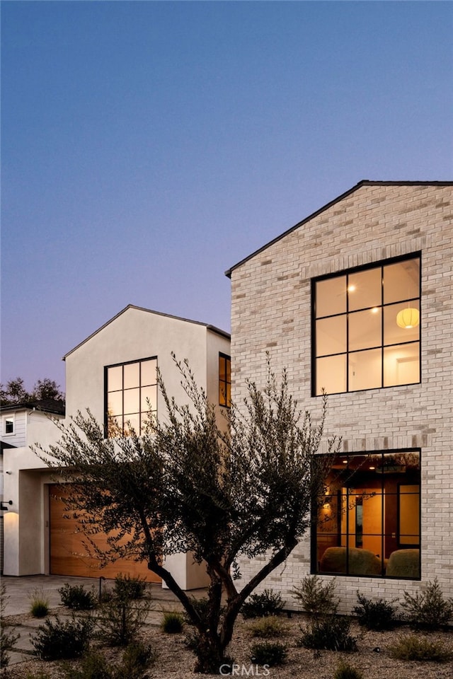 property exterior at dusk with stucco siding and a garage