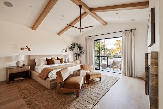 bedroom with lofted ceiling with beams, access to outside, a fireplace, and wood finished floors