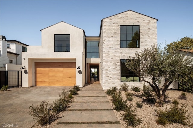 view of front of home with stucco siding, brick siding, a garage, and concrete driveway