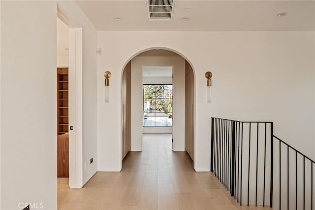 hall with recessed lighting, arched walkways, light wood finished floors, and visible vents