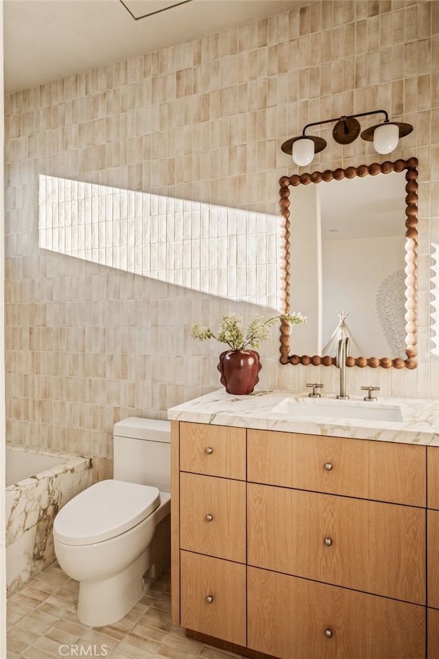 bathroom featuring toilet, vanity, a tub, tile patterned flooring, and tile walls