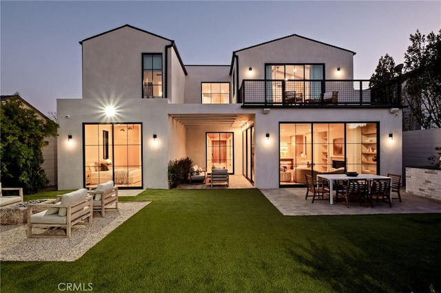 rear view of house featuring an outdoor living space, stucco siding, a balcony, a patio, and a yard