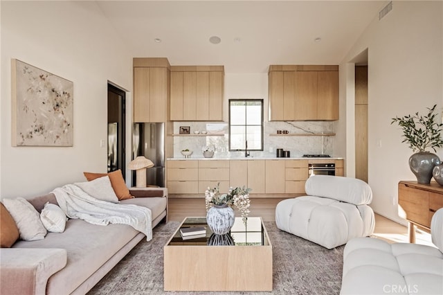 living area with wood finished floors, vaulted ceiling, and visible vents
