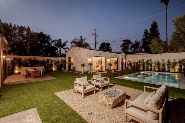 exterior space with an outbuilding, a patio, a pool with connected hot tub, outdoor lounge area, and a lawn