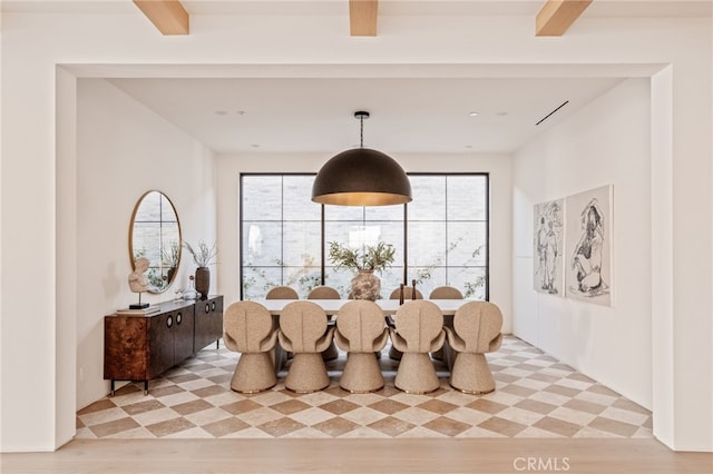 dining space with light wood-style floors and beam ceiling