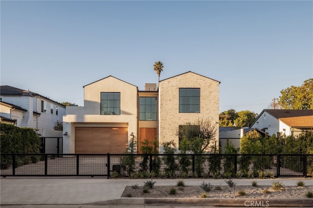 view of front facade with a fenced front yard, a garage, concrete driveway, a gate, and stucco siding