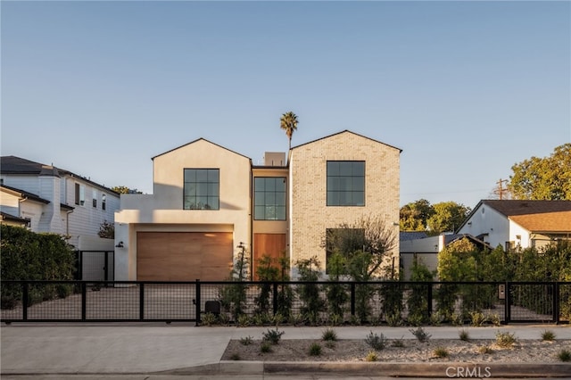 view of front facade with a gate, driveway, an attached garage, a fenced front yard, and stucco siding
