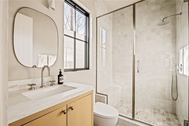 full bath with a stall shower, toilet, and vanity