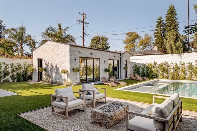 rear view of house with a yard, brick siding, a patio, and a fenced in pool