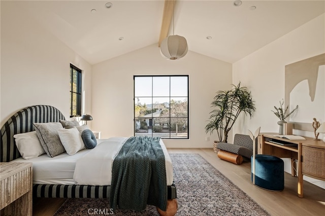 bedroom with light wood-style floors and lofted ceiling with beams