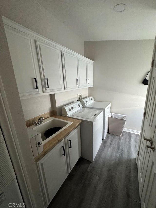 washroom featuring dark wood finished floors, a sink, cabinet space, and washer and dryer