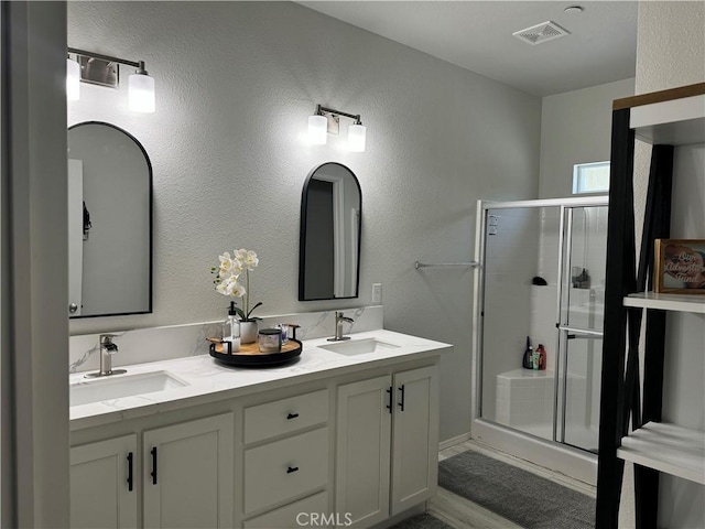 bathroom featuring a stall shower, visible vents, and a sink