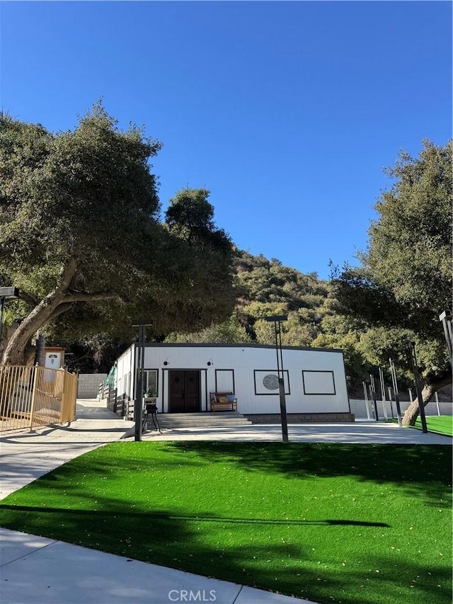 view of front facade with a front yard, a patio area, and fence