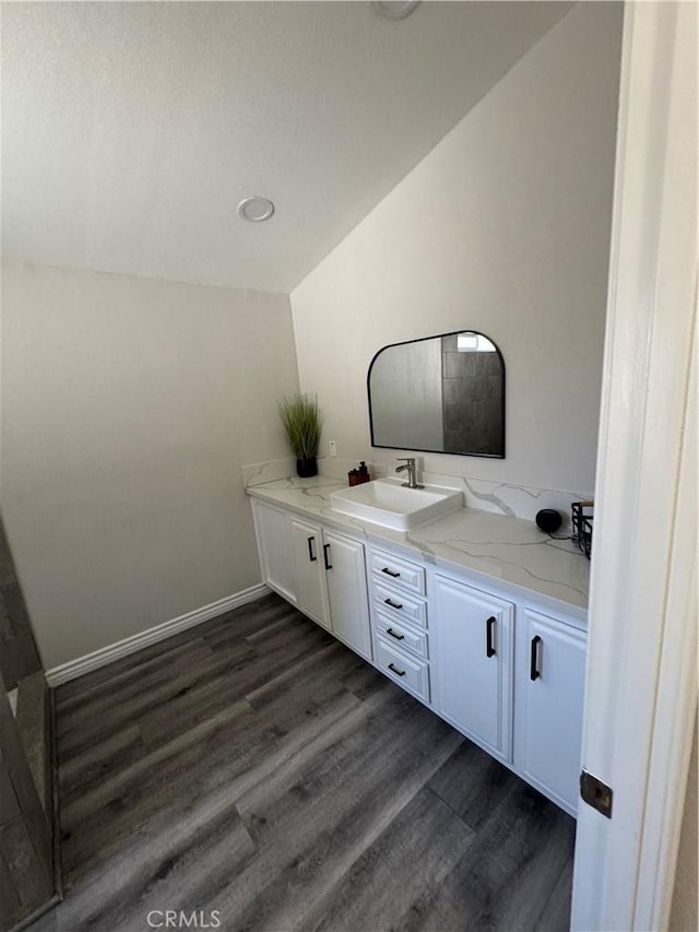 bathroom featuring lofted ceiling, wood finished floors, vanity, and baseboards