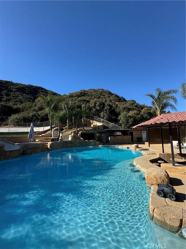 community pool with a patio area and fence