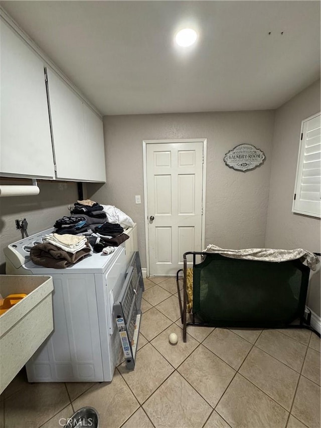 kitchen with light tile patterned floors, white cabinets, washer and dryer, and light countertops