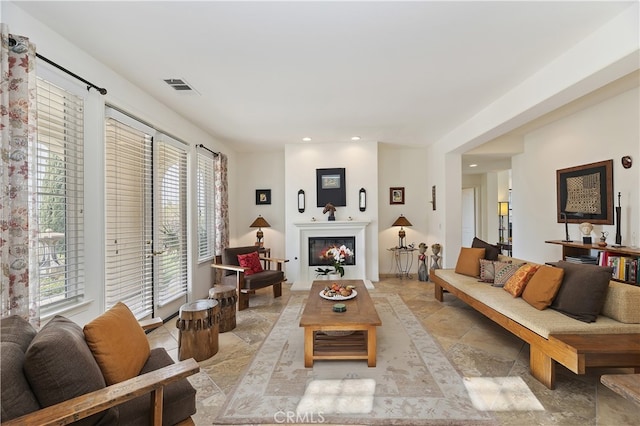 living room featuring recessed lighting, visible vents, and a glass covered fireplace