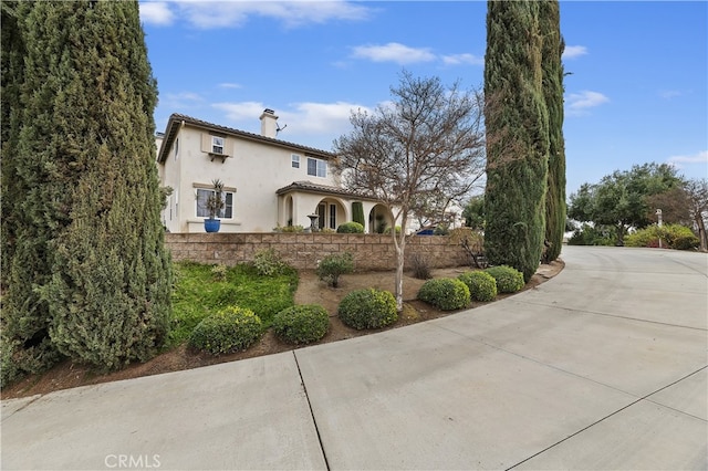 exterior space featuring stucco siding, a tile roof, a chimney, and fence