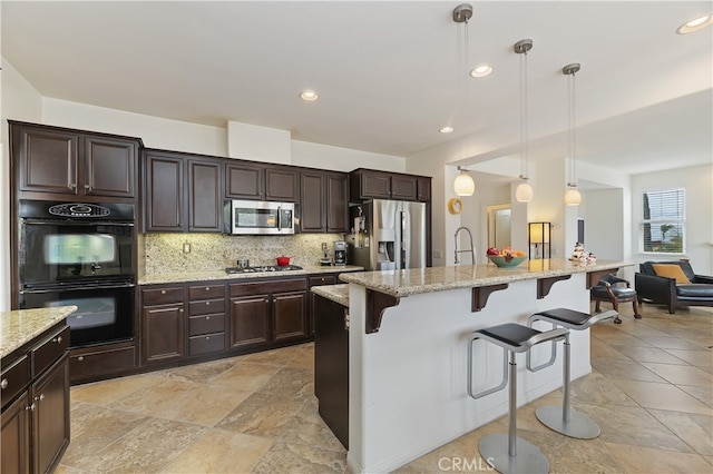 kitchen with a breakfast bar, dark brown cabinets, backsplash, and stainless steel appliances