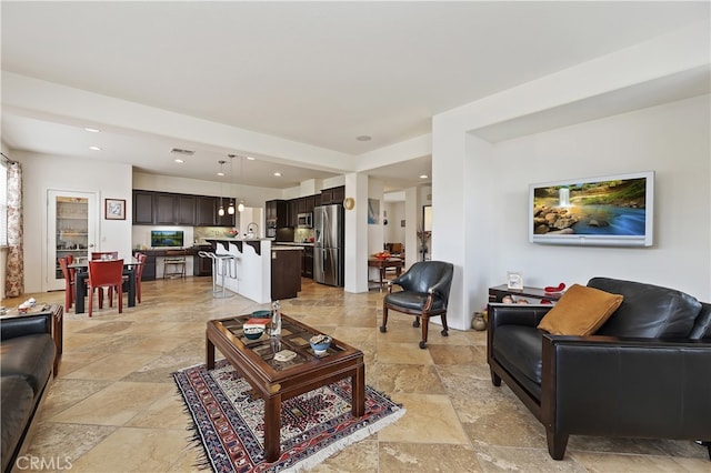 living area featuring recessed lighting, visible vents, and stone tile flooring