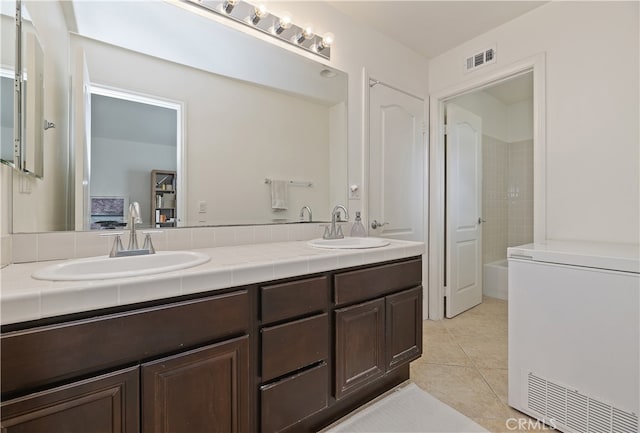 bathroom with a sink, visible vents, double vanity, and tile patterned flooring