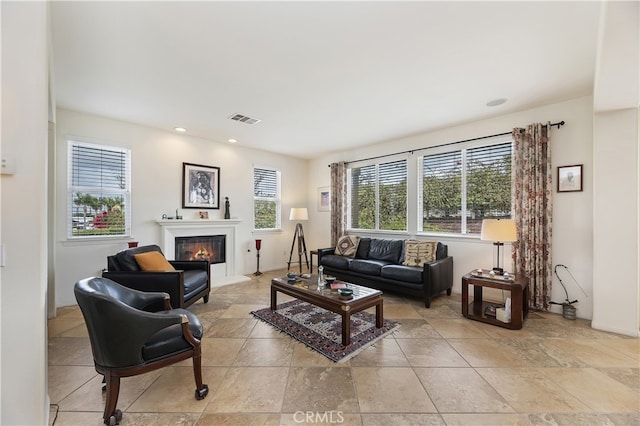 living area with a wealth of natural light, visible vents, a fireplace with flush hearth, and recessed lighting