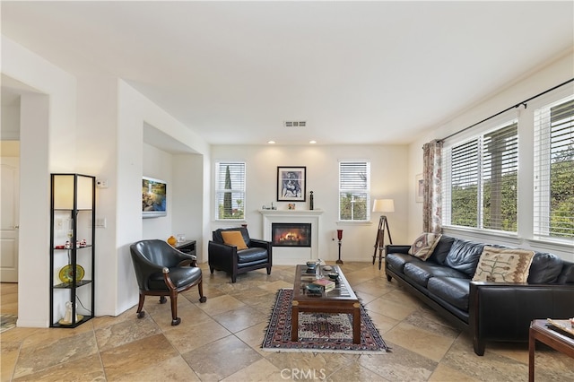 living area with recessed lighting, visible vents, plenty of natural light, and a glass covered fireplace