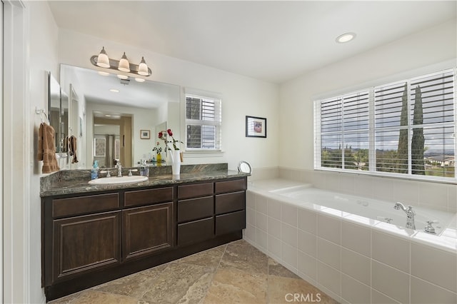 full bath featuring vanity, a bath, recessed lighting, and stone tile flooring