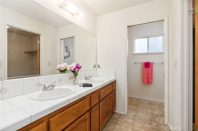 bathroom featuring double vanity, a sink, and baseboards