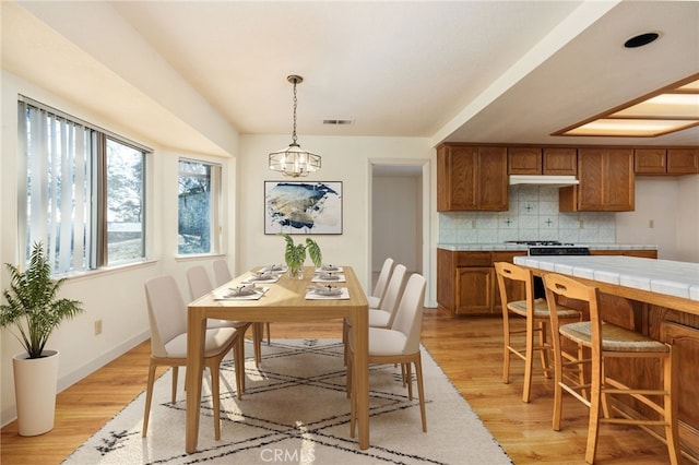 dining room featuring light wood-type flooring, an inviting chandelier, baseboards, and visible vents