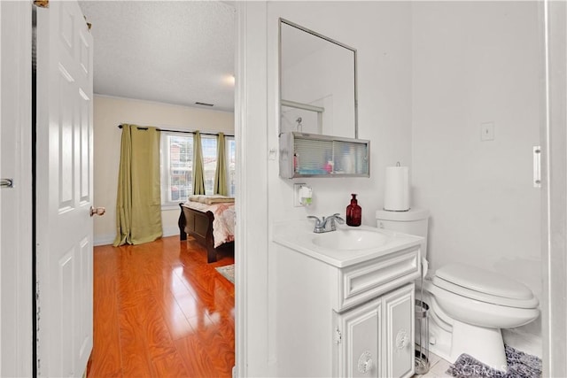 bathroom with visible vents, toilet, wood finished floors, a textured ceiling, and vanity