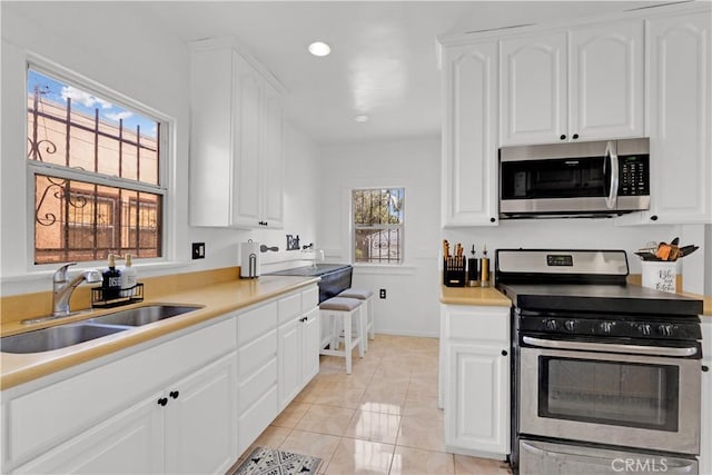 kitchen with recessed lighting, stainless steel appliances, a sink, white cabinets, and light countertops