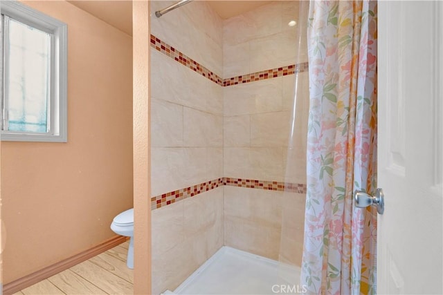 bathroom featuring baseboards, tiled shower, and toilet