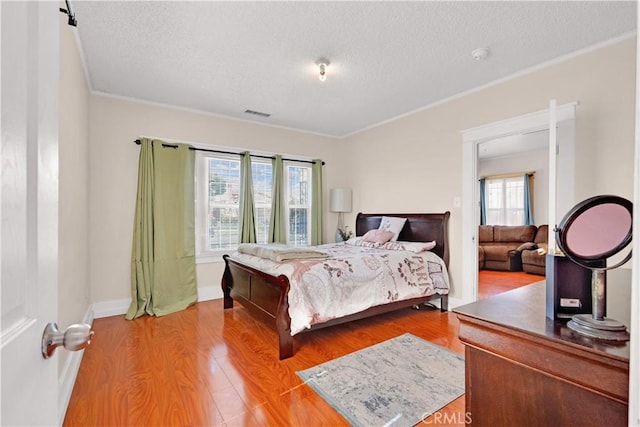 bedroom with visible vents, light wood-style flooring, and a textured ceiling