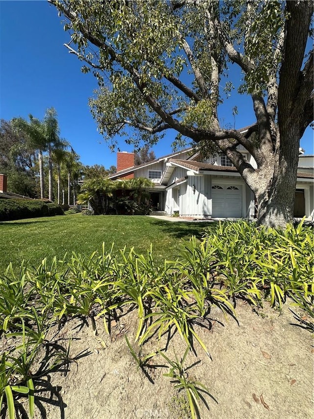 view of front of home featuring a garage, a front lawn, and a chimney