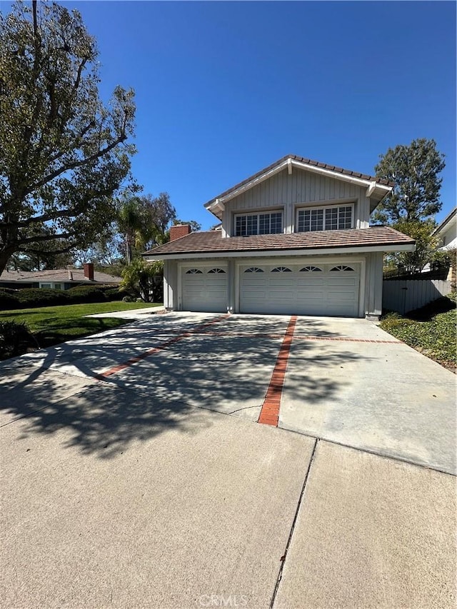 view of front of house featuring concrete driveway and fence