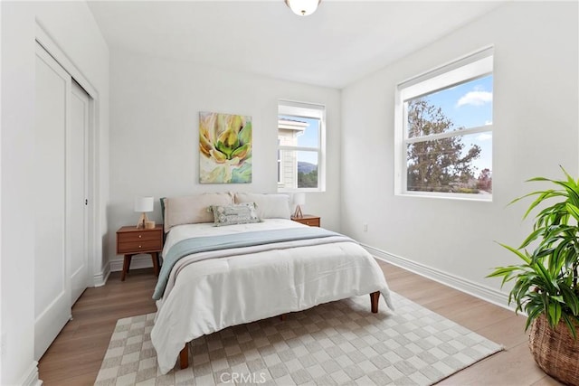 bedroom featuring a closet, baseboards, and light wood finished floors