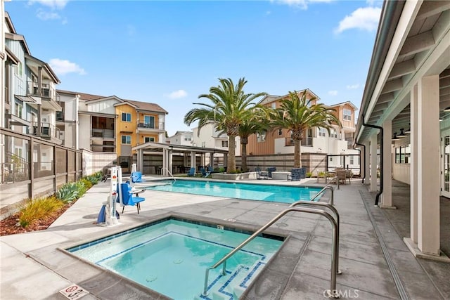 pool featuring a patio area, a community hot tub, fence, and a residential view