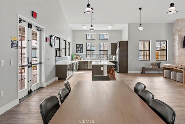 dining space featuring french doors, light wood-type flooring, and baseboards