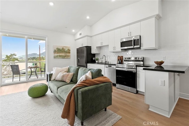 kitchen with a sink, stainless steel appliances, dark countertops, and open floor plan