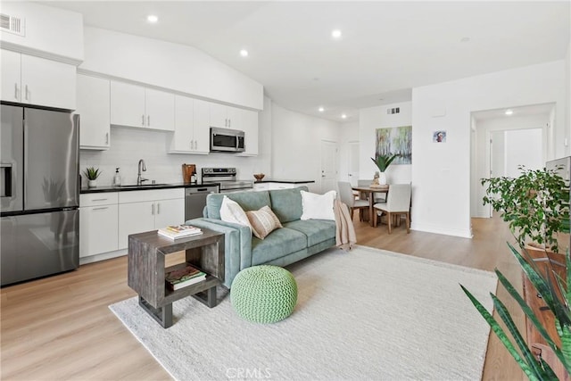 living area with vaulted ceiling, recessed lighting, visible vents, and light wood-type flooring