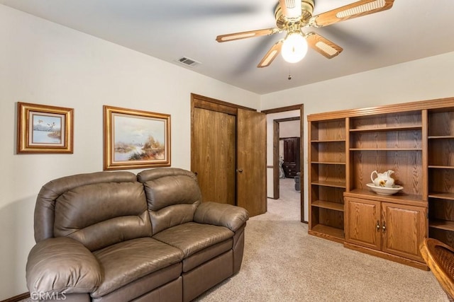 living area featuring a ceiling fan, visible vents, and light colored carpet