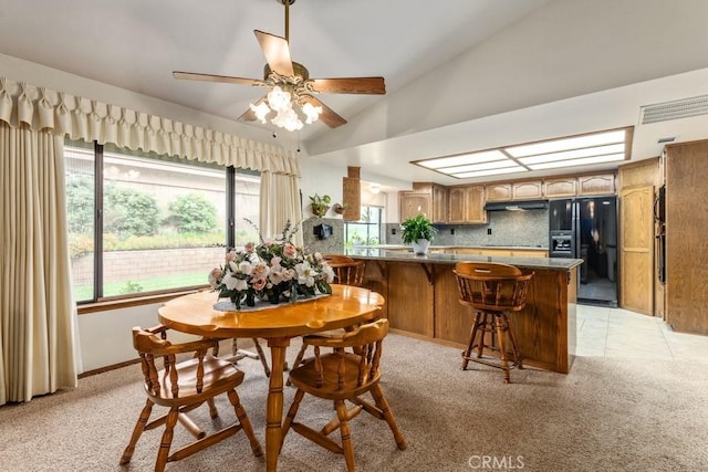 dining room with a ceiling fan, lofted ceiling, and light colored carpet