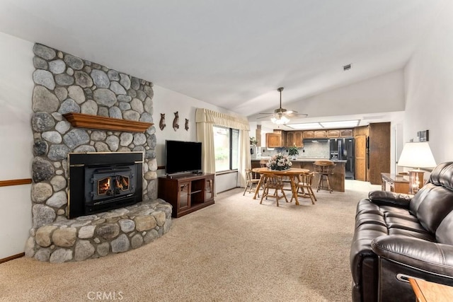 living room featuring high vaulted ceiling, a stone fireplace, light colored carpet, a ceiling fan, and visible vents