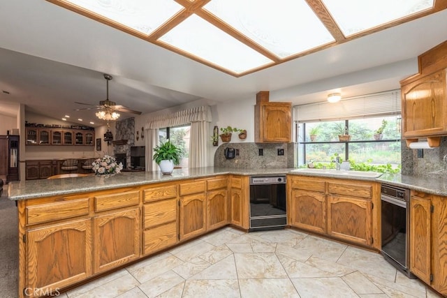 kitchen with black dishwasher, brown cabinets, tasteful backsplash, a sink, and a peninsula