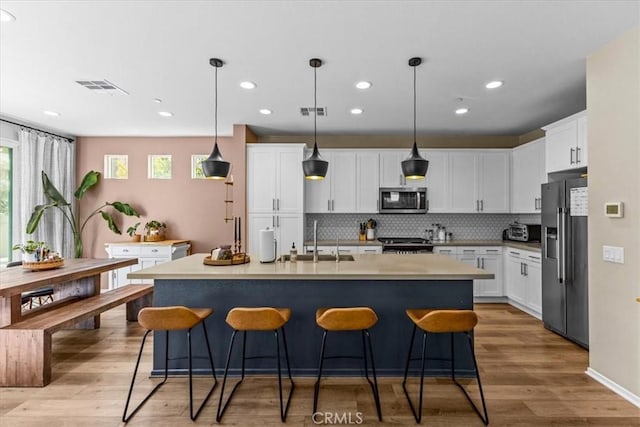 kitchen with appliances with stainless steel finishes, visible vents, a sink, and a breakfast bar area