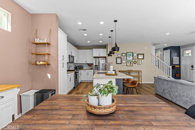 dining space with recessed lighting, visible vents, stairway, and wood finished floors