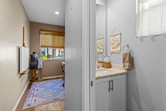 bathroom featuring a textured wall, baseboards, wood finished floors, and vanity