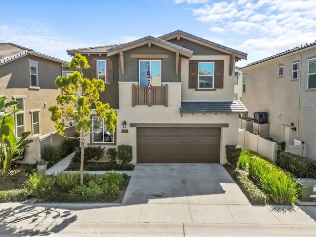 view of front facade featuring concrete driveway, a tile roof, an attached garage, and stucco siding